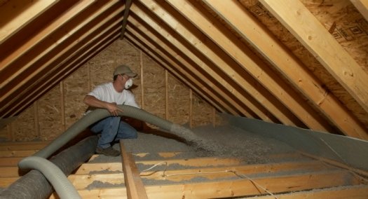 Professional contractor blowing cellulose insulation into attic